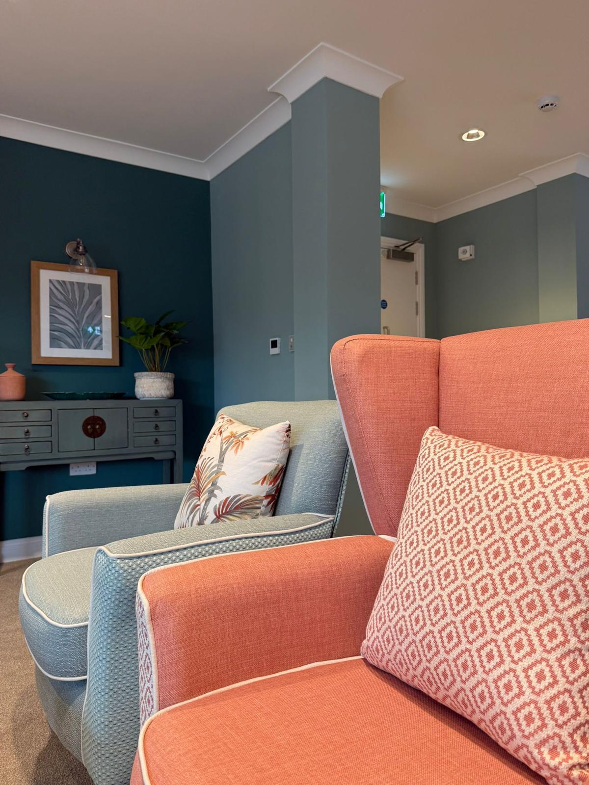 A bright living space with coral and teal furniture at Oadby Manor