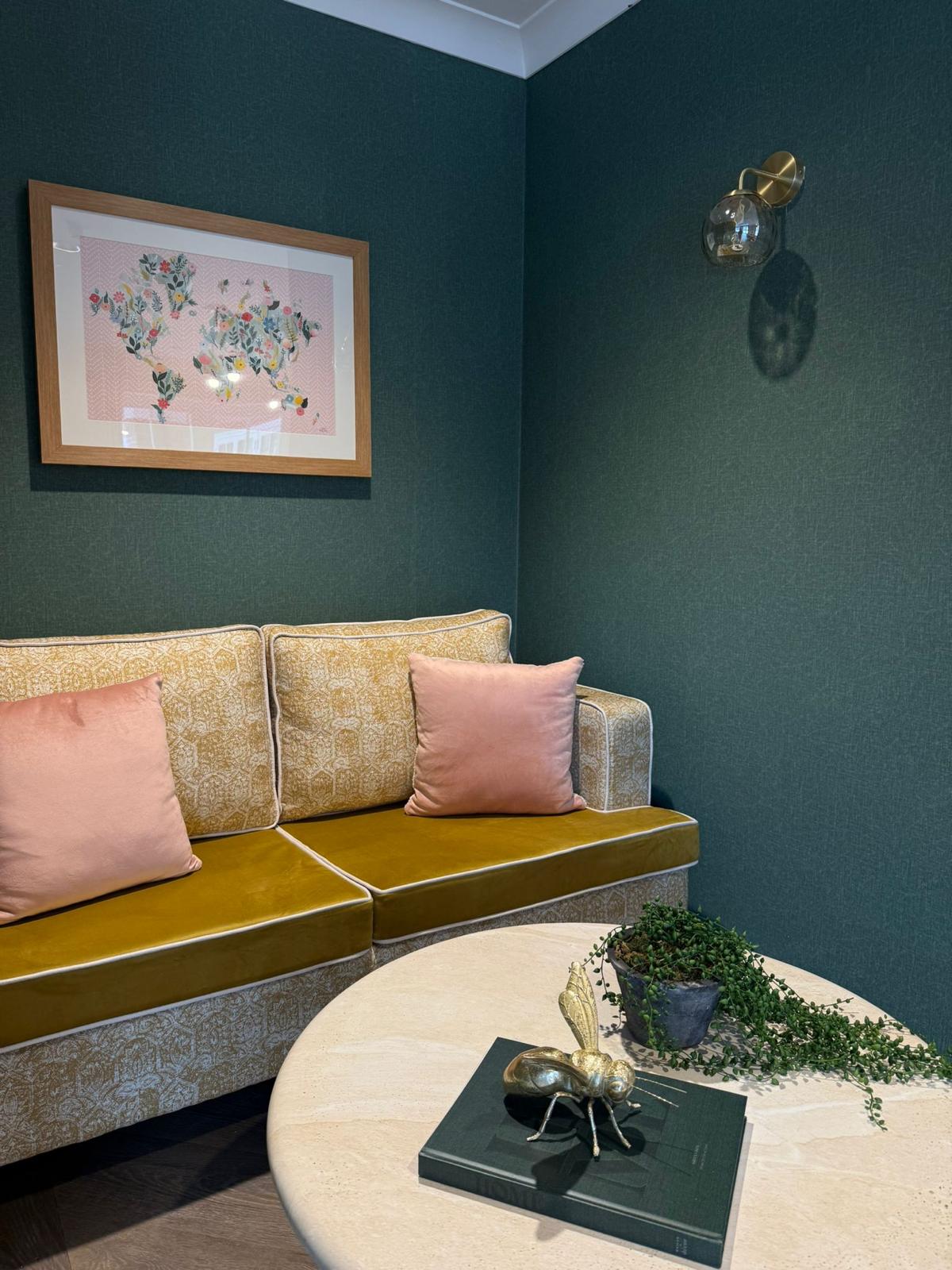 A cosy snug at Oadby Manor with yellow sofa and floral artwork